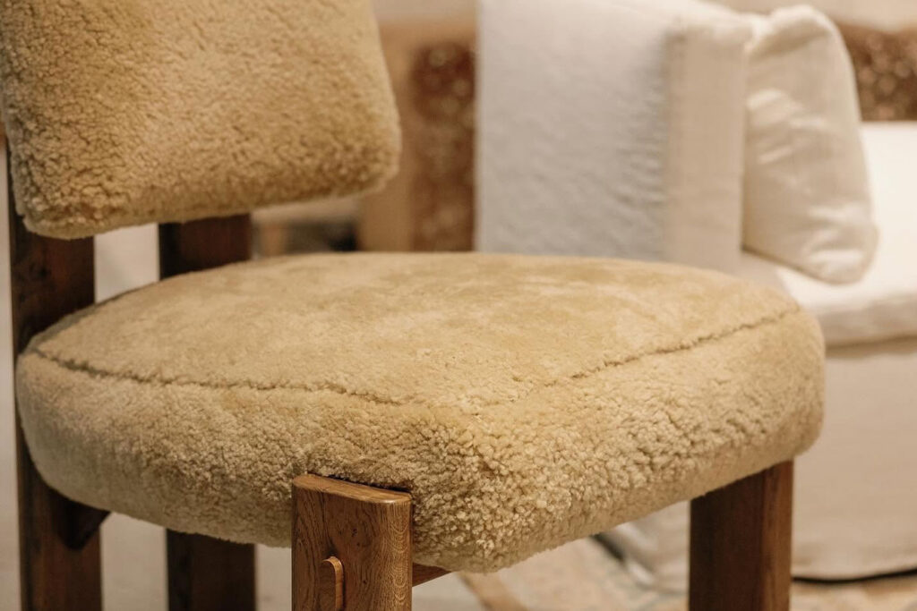 Close-up of an oat-colored bouclé accent chair with nubby textured upholstery and a natural wood frame at Fowler Brothers Co. furniture showroom in Chattanooga Tennessee