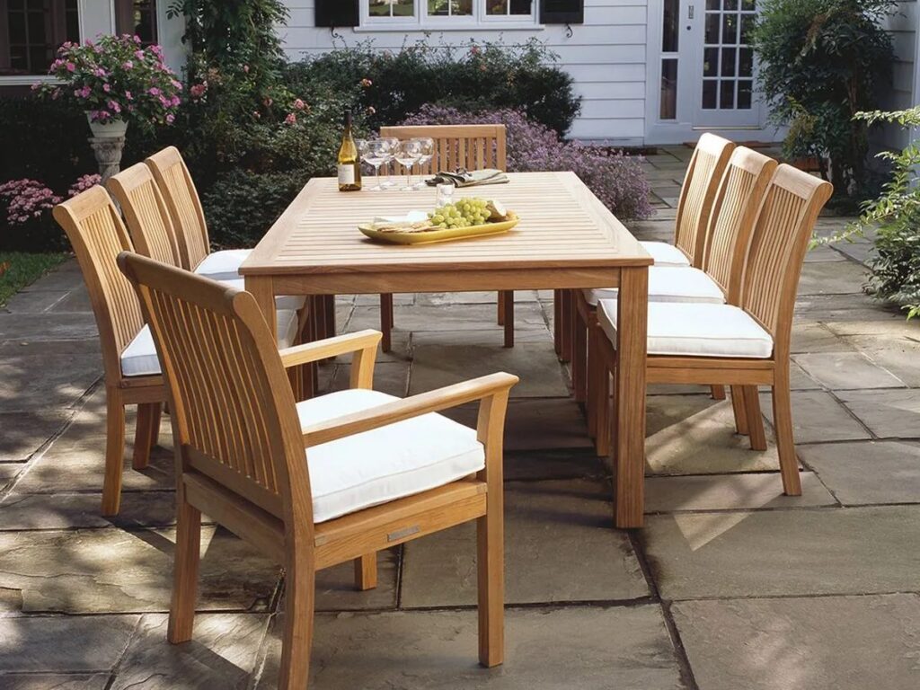 Plantation teak outdoor dining furniture set with rectangular table and six cushioned chairs on a backyard patio near Chattanooga