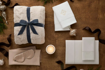 A cozy holiday gift set featuring a plush blanket, luxury bedding, and candles, perfect for holiday gifting ideas